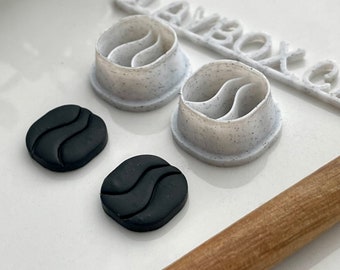 May include: Two black silicone molds with a wavy design and two black silicone shapes with a wavy design. The molds are on a white surface with a rolling pin and a white plastic sign that says "Claybox.ca".