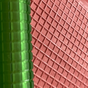 Puede incluir: Primer plano de una superficie texturizada verde y roja. La superficie verde tiene una textura acanalada y la superficie roja tiene un patrón de diamante.