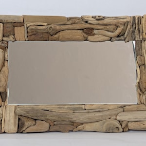 Peut inclure: Un miroir rectangulaire doté d'un cadre composé de divers morceaux de bois flotté patiné dans des tons de beige, de brun et de sable. Le cadre est formé de multiples petits segments de bois irréguliers entourant la vitre centrale.