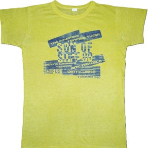 Könnte beinhalten: Ein gelbes T-Shirt mit einem blauen Grafikdesign. Das Design enthält den Text "SON OF STIFF 80", "THE EQUATORS" und "BUFFALO STATE SOCIAL HALL". Das Datum "9 DECEMBRE 1980" ist ebenfalls zu sehen.