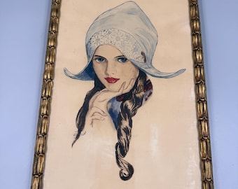 May include: A vintage framed watercolor portrait of a woman wearing a light blue bonnet with lace trim. The woman has blue eyes, red lips, and long dark hair. The frame is gold-colored.