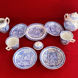 May include: A blue and white porcelain tea set with a sugar bowl, creamer, and four teacups and saucers. The set features a whimsical design with a repeating pattern of figures and flowers.