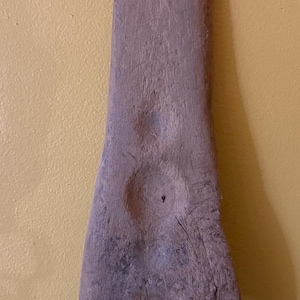 May include: A weathered, wooden tool with a long, rectangular handle and a forked base. Three circular holes are drilled near the top. The wood has a natural, aged appearance with visible grain and knots. The tool is likely vintage.