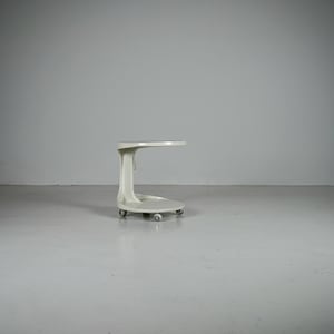 May include: A white C-shaped side table with a smooth, curved frame and a circular base. The table features a single vertical support column connecting the top surface to the base, which is equipped with small, functional castors for mobility.