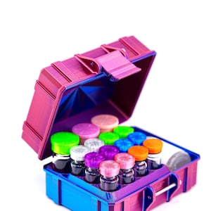 May include: A small, open, purple and blue case with a variety of small glass bottles with colorful lids. The case is rectangular with a hinged lid and a clasp. The bottles have green, pink, purple, and orange lids.