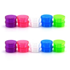 May include: A collection of small, colorful, round objects in purple, pink, white, blue, and green. The objects appear to be made of plastic and have a textured surface. The items are arranged in two rows on a white background.