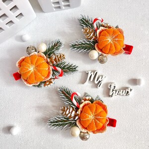 May include: Three festive hair clips with orange felt mandarin orange slices, pine needles, candy canes, and decorative accents. Each clip has a red ribbon base. The words "My bows" are in the image.