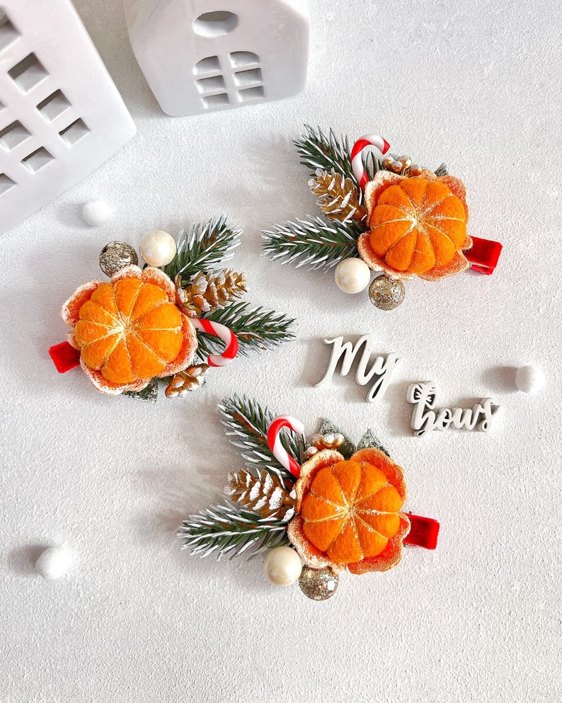May include: Three festive hair clips with orange felt mandarin orange slices, pine needles, candy canes, and decorative accents. Each clip has a red ribbon base. The words "My bows" are in the image.