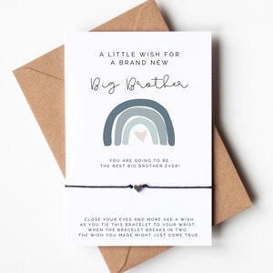 May include: A white card with the text "A Little Wish For A Brand New Big Brother" and a blue rainbow graphic. A black string bracelet with a heart charm is attached. The card is on a brown envelope.