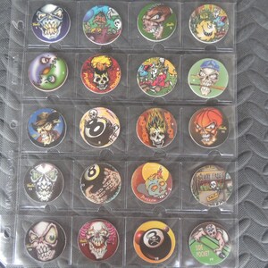 May include: A collection of 19 round, colorful, plastic poker chips with various skull and 8-ball designs. The chips are displayed in a clear plastic sheet with numbered slots.