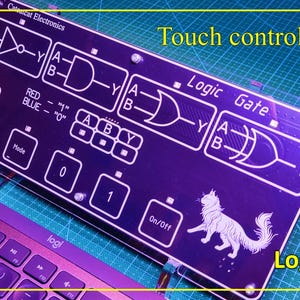 May include: A rectangular black electronic circuit board featuring white printed logic gate diagrams, including NOT, AND, OR, and XOR symbols. The board displays the text Catscat Electronics, Logic Gate, and On/Off, with a cat illustration and touch control buttons.