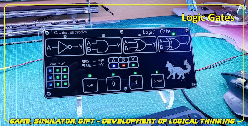 May include: A black rectangular electronic logic gate simulator board with white printed circuit diagrams, including NOT, AND, OR, and XOR symbols. The device features a grid of green LED indicators, a cat graphic, and buttons labelled Mode, 0, 1, and On/Off.