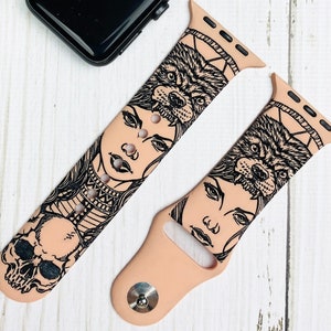 Puede incluir: Dos correas rosas para Apple Watch con un estampado gráfico en blanco y negro de la cara de una mujer con cabeza de lobo. El estampado gráfico es una ilustración estilizada de una mujer con cabeza de lobo y una calavera.