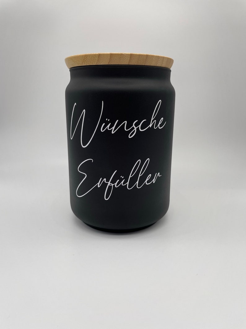May include: Black jar with a wooden lid and white text that reads "W&uuml;nsche Erf&uuml;ller".