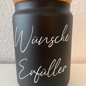 May include: Black jar with a bamboo lid and white lettering that says "W&uuml;nsche Erf&uuml;ller".