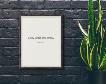 May include: A framed print with a black frame hanging on a dark brick wall. The print features the quote "Crazy world, lotta smells." by Michael Scott.