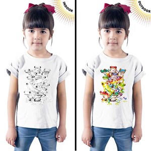 May include: A white t-shirt with a design of a stack of frogs. The frogs are black and white indoors and colorful outdoors. The text "INDOOR" and "OUTDOOR" is visible on the image.