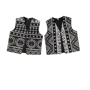 May include: Two black sleeveless vests with white geometric patterns. The vests have a V-neck and are made of a soft, lightweight fabric.