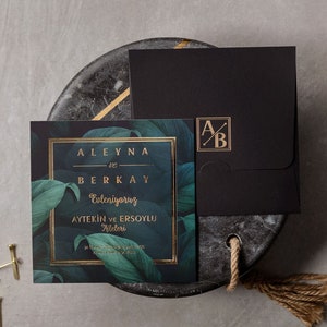 Invitación de boda con hojas verdes, primeras letras impresas con impresión tipográfica en papel dorado, sobre negro, tarjeta de invitación enmarcada con impresión tipográfica en papel dorado