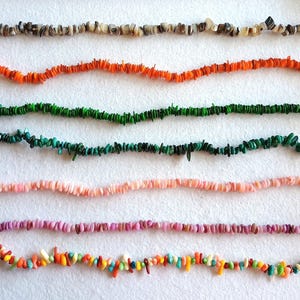 May include: Six strands of colorful, small, irregular-shaped beads. The strands are in shades of brown, orange, green, teal, pink, purple, and a multicolored strand with yellow, orange, and green beads. The beads are strung on thin wire.