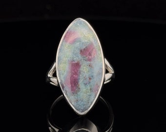 May include: A silver ring with a marquise-shaped gemstone. The gemstone is a mix of pink, blue, and green colors.
