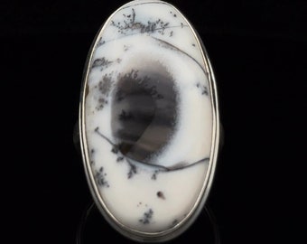 Può includere: Un anello d'argento con una pietra ovale in agata dendritica bianca e nera. La pietra presenta un motivo a spirale di dendriti nere su uno sfondo bianco.