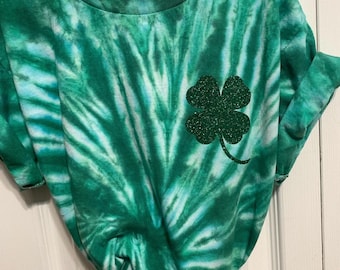May include: Green tie-dye t-shirt with a sparkly green four-leaf clover design.