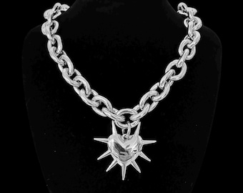 May include: A silver chain necklace with a large, spiked heart pendant.