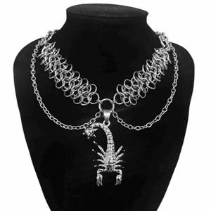 May include: A silver chain necklace with a scorpion pendant. The chain is made of small, interlocking rings and has a layered look. The scorpion pendant is detailed and has a realistic design.