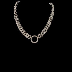 May include: Silver-toned chain necklace with a large circular pendant. The necklace features a double-strand chain design with a series of interlocking links. The pendant is a simple, polished ring. The jewelry is set against a black background.