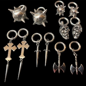 Pode incluir: Um conjunto de 10 peças de joalheria corporal de prata, incluindo um par de bolas com espinhos, um par de pingentes de caveira, um par de pingentes de cruz e um par de pingentes de machado. Cada pingente está preso a um anel de prata.