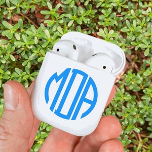 May include: White Airpods case with a blue monogram sticker that says "MJA" in a circle.
