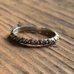 May include: A silver ring with a textured band of small, raised dots.