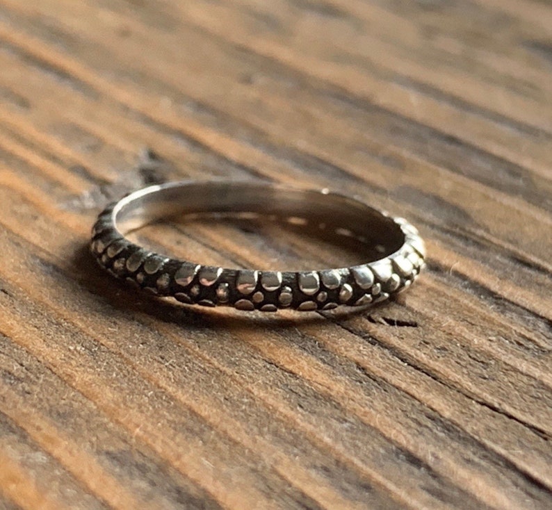 May include: A silver ring with a textured band of small, raised dots.