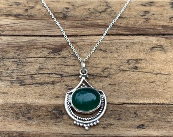 May include: A silver necklace with a green gemstone pendant. The pendant is in a teardrop shape with a detailed silver design.