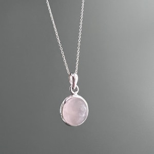 May include: A silver chain necklace with a round pink rose quartz pendant.