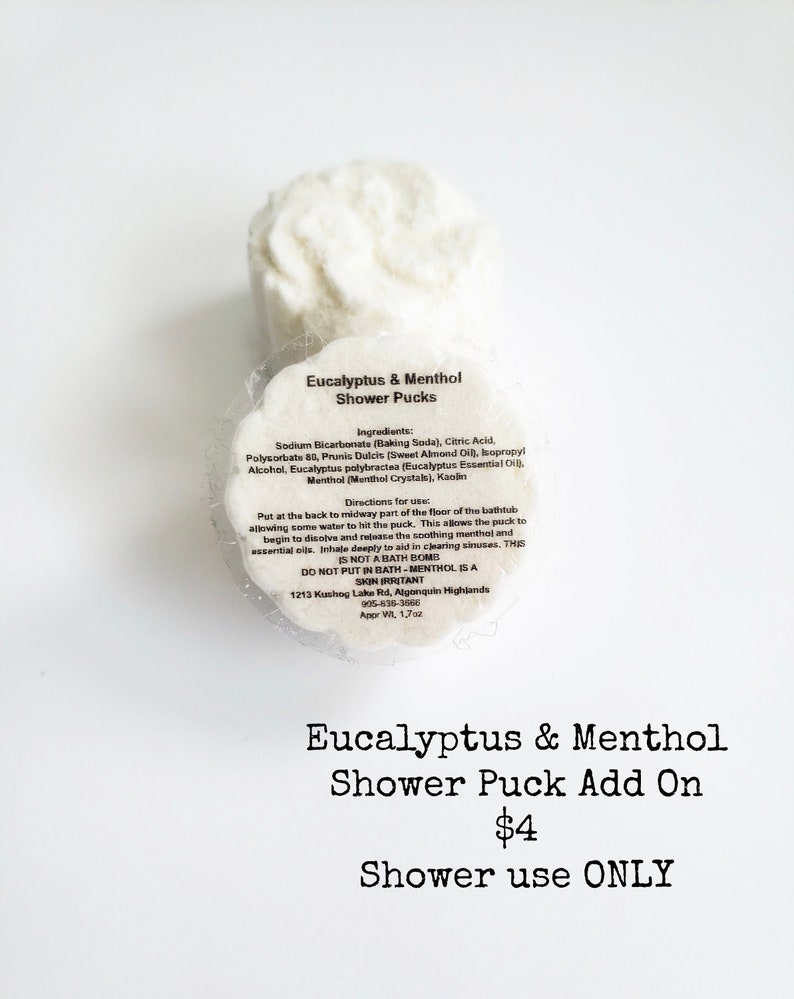 May include: Two white shower pucks with the text "Eucalyptus & Menthol Shower Pucks" and a list of ingredients and directions for use. The text "Eucalyptus & Menthol Shower Puck Add On $4 Shower use ONLY" is below the image of the pucks.