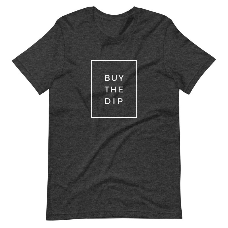 May include: A dark heather grey t-shirt with a white box and the text "BUY THE DIP" inside the box.