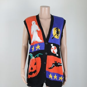 Pu&ograve; includere: Un gilet di maglina nero senza maniche con un design di Halloween colorato. Il gilet presenta una zucca, un fantasma, un pipistrello, una strega, una canna di zucchero e stelle.
