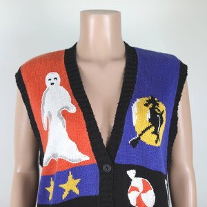 Pu&ograve; includere: Un gilet di maglia senza maniche con un design a patchwork colorato che presenta un fantasma, una strega, stelle e una canna di zucchero. Il gilet ha un collo a V nero e una chiusura con bottone.