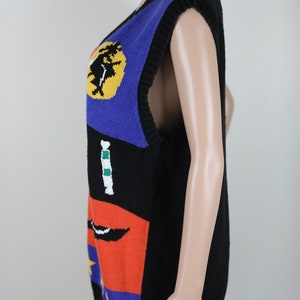 Pu&ograve; includere: Un gilet senza maniche in maglia con un motivo geometrico colorato. Il gilet &egrave; nero con accenti blu, giallo, rosso, verde e bianco.
