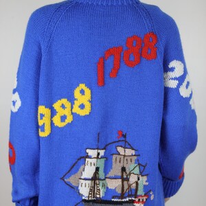 May include: Blue knitted sweater with a ship, clouds, and the numbers 1788 and 988 embroidered on it.