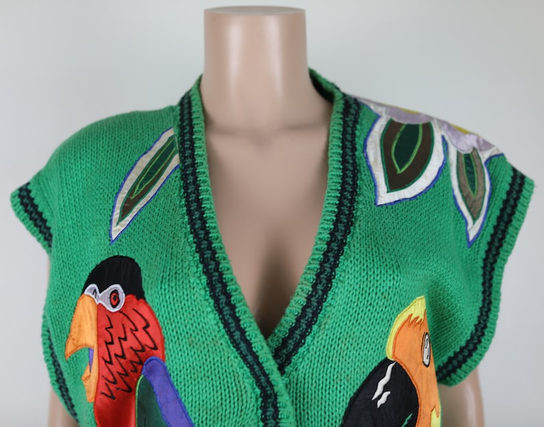 Puede incluir: Chaleco de punto verde sin mangas con cuello en V y p&aacute;jaros y flores bordados de colores.