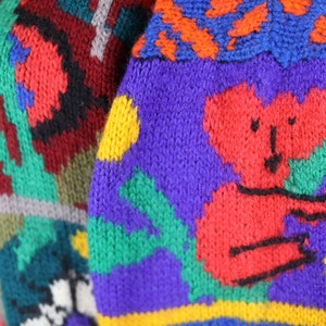 May include: A colorful knitted sweater with a red koala bear design. The sweater features a variety of colors, including red, blue, green, yellow, and purple.