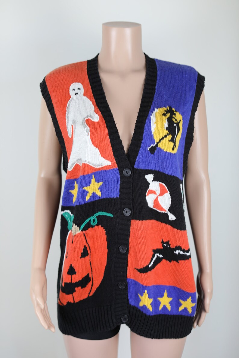 Pu&ograve; includere: Un gilet di maglina nero senza maniche con un tema di Halloween colorato. Il gilet presenta un fantasma, una strega, una zucca, bastoncini di zucchero e pipistrelli. Il gilet ha un collo a V e bottoni sul davanti.