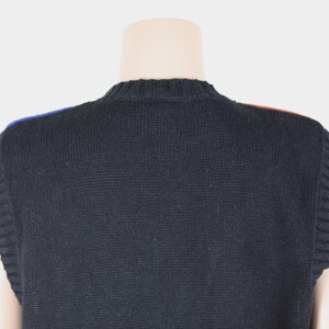 Pu&ograve; includere: Gilet di maglia nero senza maniche con un bordo blu e rosso intorno al collo.