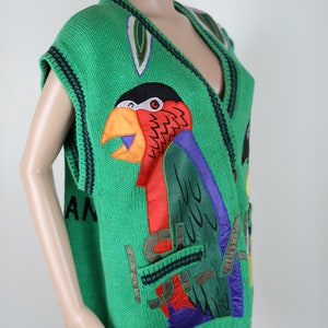 Puede incluir: Su&eacute;ter verde sin mangas con un dise&ntilde;o de loro y la palabra "Island" en la parte delantera. El loro est&aacute; hecho de tela colorida y tiene un pico grande.