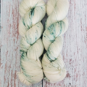 以下が含まれることがあります： クリーム色に緑の斑点が入った糸の糸巻きが2つ。糸はねじり合わされています。