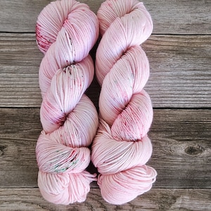 May include: Two skeins of pink yarn with red and white flecks. The yarn is soft and fluffy, and it would be perfect for knitting or crocheting.