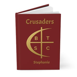 May include: A maroon journal with the word "Crusaders" in gold lettering. A gold emblem with the letters B, T, S, and C is centered below the word. The name "Stephanie" is printed in gold at the bottom.